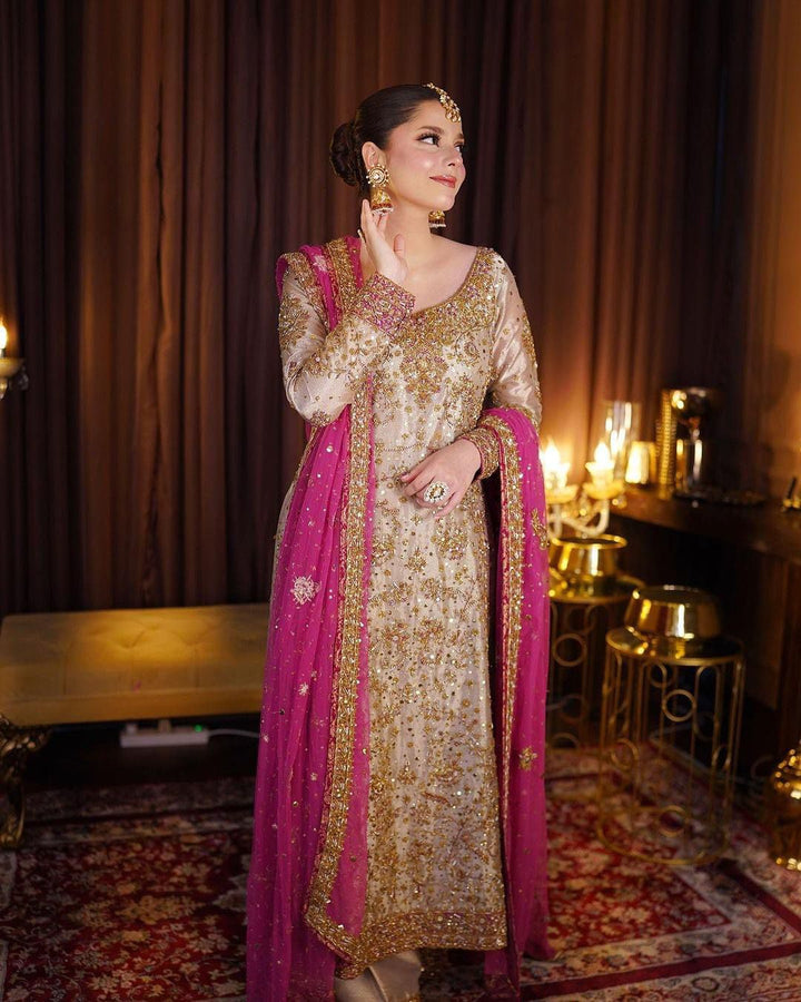 Haris Shakeel Gold & Pink pakistani indian wedding bridal dress, mehndi nikkah oufits guest suits
Product Description: Haris Shakeel embodies a white color on an net, which features intricate embroidery inspired by nature’s floral composition all over. Further layered with mesmerizing embellishments of sequins, pearls, and crystals. The outfit is paired with a modern look flared pants, and a sophisticatedly embroidered dupatta concluded with minimalistic borders, making this ensemble just the perfect choice